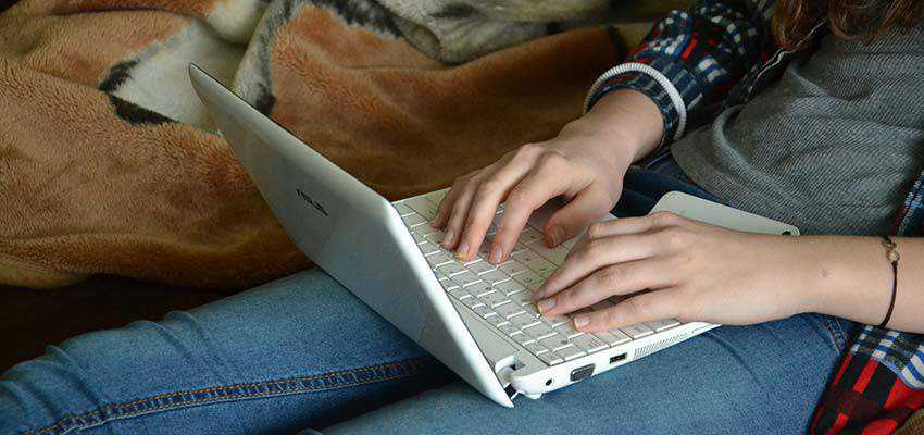 Woman typing on a laptop computer.