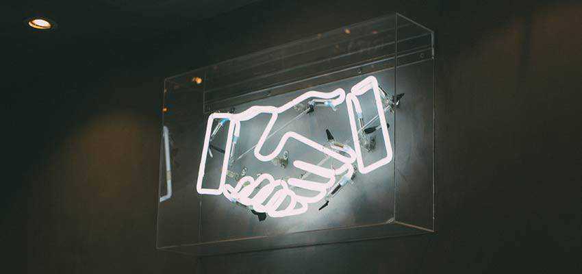 A neon sign depicting a handshake.